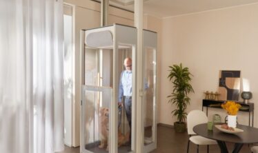 En middelaldrende mann med hunden sin i en Uplifts S3 installert i en moderne stue.