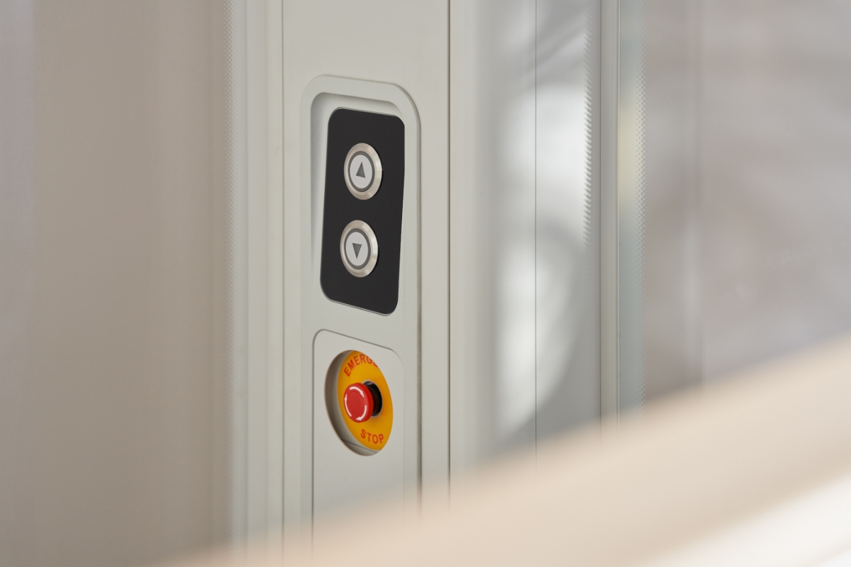 Nærbilde av kontrollpanelet i en Stannah Uplifts-boligheis, med knapper for opp og ned samt en rød nødstopp for trygg bruk.